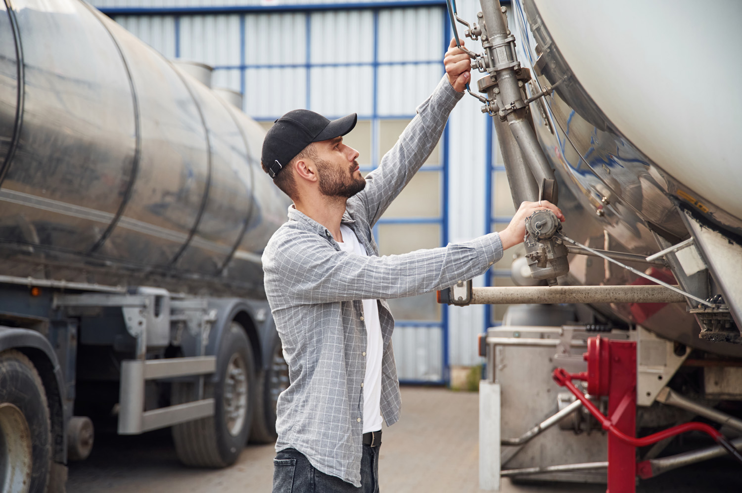 Between two vehicles. Young truck driver in casual clothes.