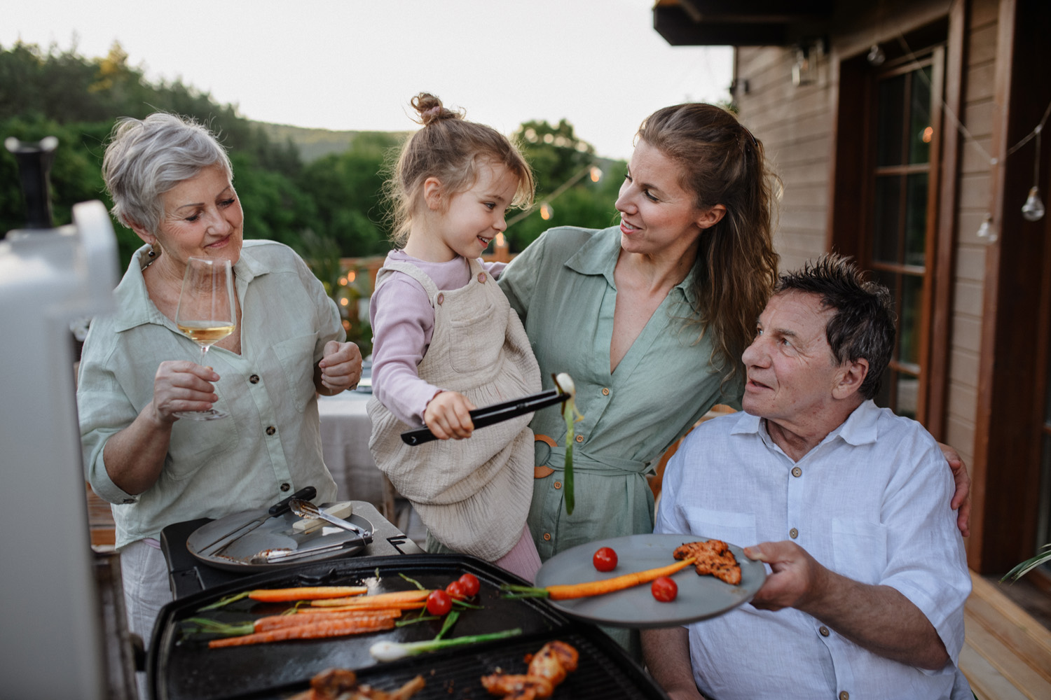 Multi generation family grilling outside on patio in summer during garden party Family grilling