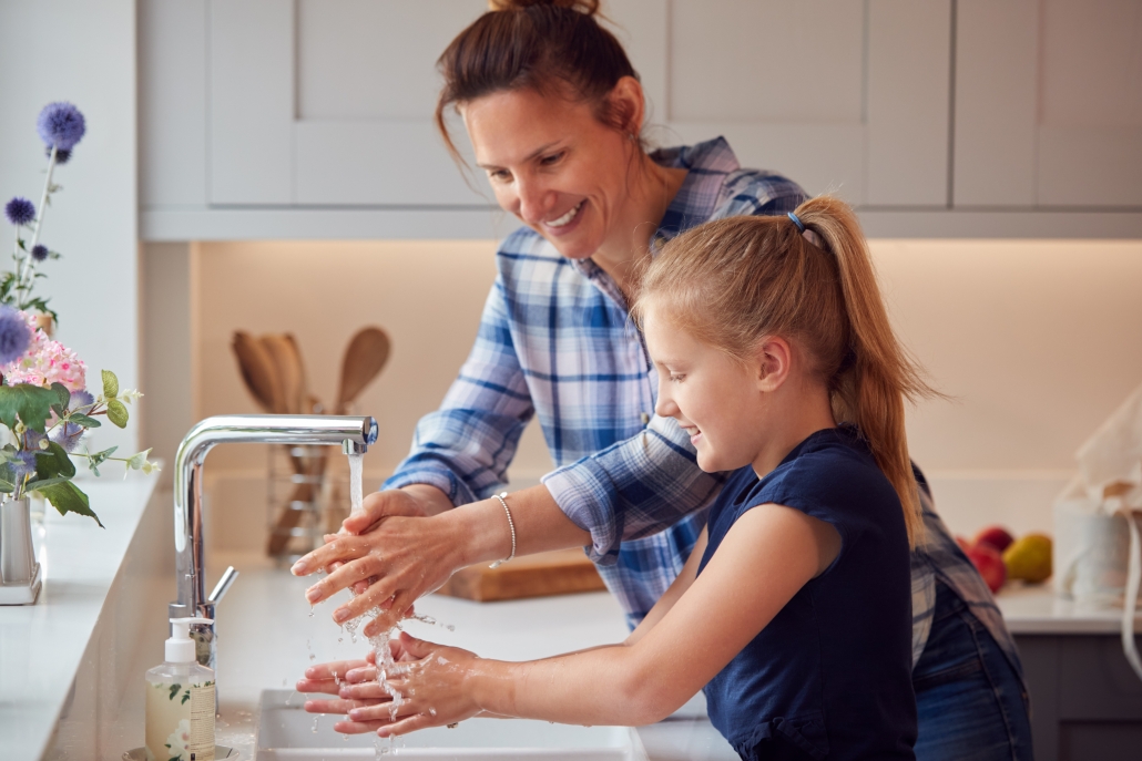 mother and daughter using hot water at sink